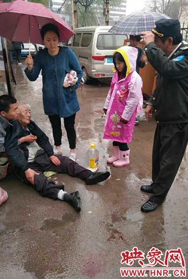 女孩為倒地老人撐傘。