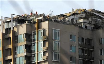 　　昨日，身穿橘黃色馬甲的工作人員在人濟山莊樓頂拆除違章建筑。新京報記者 吳江 攝