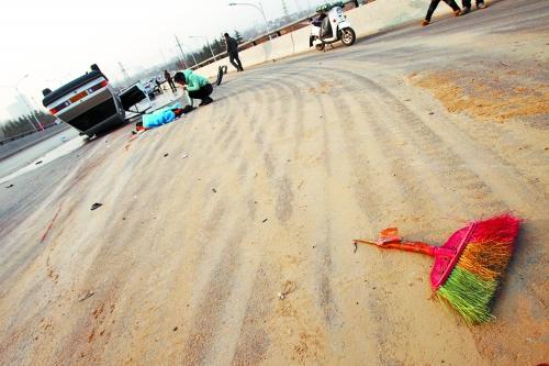 被撞的環(huán)衛(wèi)工躺在地上，身上蓋著藍(lán)色布?jí)K，現(xiàn)場(chǎng)除散落的汽車碎片外，還留有被撞斷的掃帚。