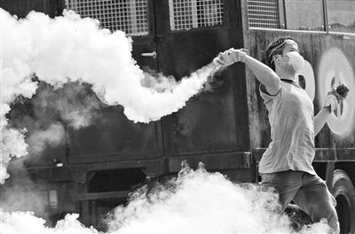 12月2日，泰國曼谷，一名反政府示威者在總理府附近向負(fù)責(zé)執(zhí)勤的警察投擲催淚彈。英拉請求示威者不要再試圖占領(lǐng)政府工作部門，不要逼迫政府工作人員選邊站。