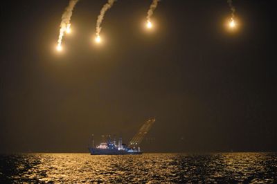 22日，搜救人員在照明彈的光亮下連夜搜救。