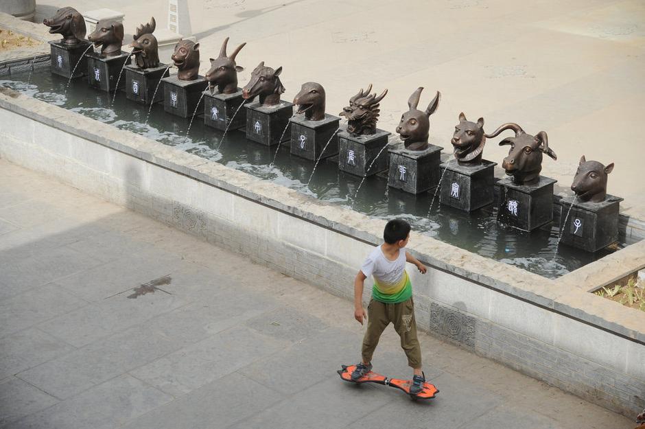 圖為一名市民從獸首旁經(jīng)過。