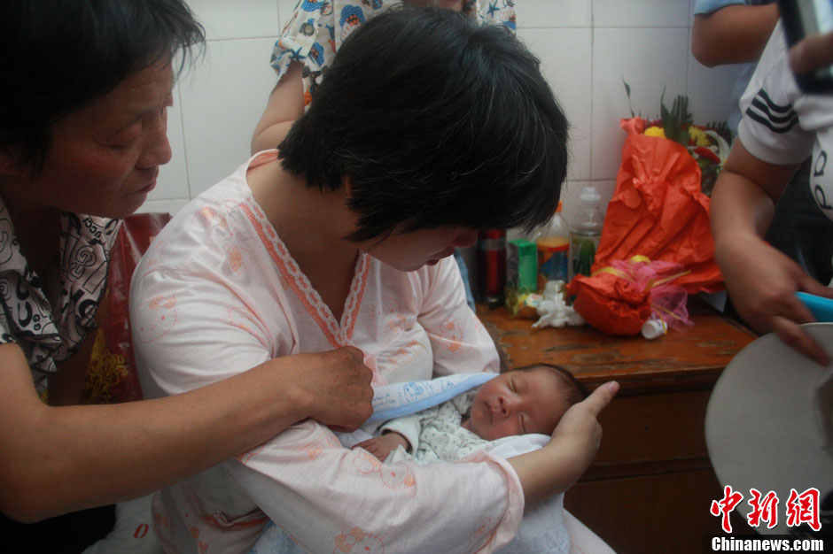 圖為久別重逢，獲救嬰兒母親悉心撫摸愛子。張一辰 攝