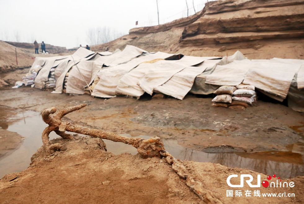 2014年1月6日，河南洛陽古沉船發(fā)掘現(xiàn)場，古沉船鐵錨從見天日，靜靜地躺在古船旁。