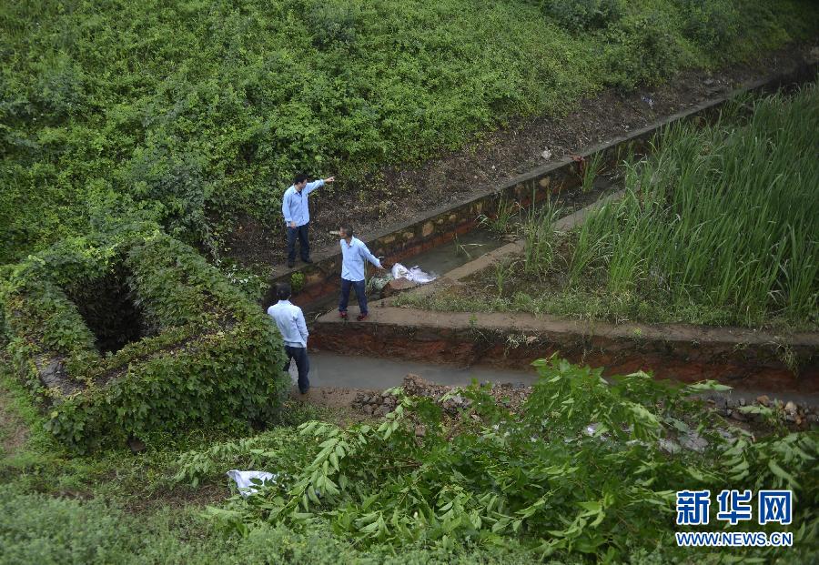 5月18日，工作人員在槽罐車泄漏現(xiàn)場(chǎng)附近的水渠邊查看情況。