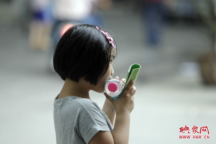 6月7日，鄭州回中考點(diǎn)，一名孩子拿著一瓶礦泉水，等待哥哥走出考場(chǎng)