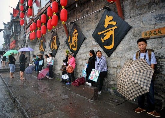 　4月29日上午11時(shí)20分，一些游客和古城當(dāng)?shù)氐木用穸阍谝粋€(gè)酒吧的屋檐下避雨。這些當(dāng)?shù)鼐用褚詾橛慰团恼罩\生，一場降雨讓他們的生意更加清淡。