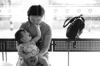 昨日，肯德基京廣中心店門口，姜女士提起跟養(yǎng)父母的關(guān)系時落淚，懷中9個月的女兒笑著跟她玩。新京報記者 薛珺 攝