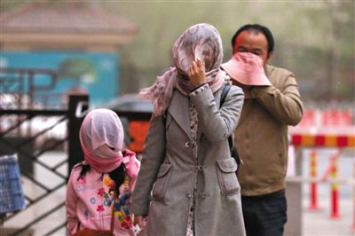 昨日下午，朝陽區(qū)豆各莊，行人將紗巾裹在頭上防沙塵。