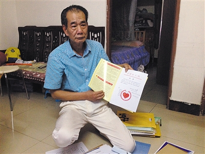 翻出一家網(wǎng)站贈(zèng)予的“中國(guó)好人”證書，區(qū)少坤單膝跪在地上，“你看，我是中國(guó)好人啊?！?范春旭 攝