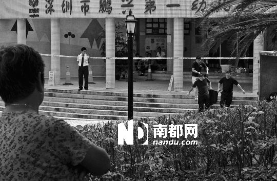 →7月19日，鵬興花園第一幼兒園門前，民警在現場進行完勘查取證后，園長和保安的尸體被運走。南都記者 徐文閣 攝