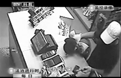 戴帽男子一手掐住加油站營業(yè)員，一手持發(fā)令槍指向另一營業(yè)員，要求“把錢給我裝起來”。