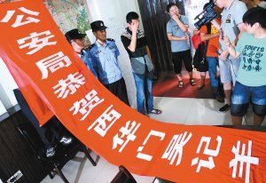 面對警方收繳的條幅，老板楊某也不好意思地用手遮擋臉