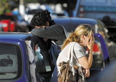 27日，遇難者親友在火災(zāi)現(xiàn)場旁哭泣。