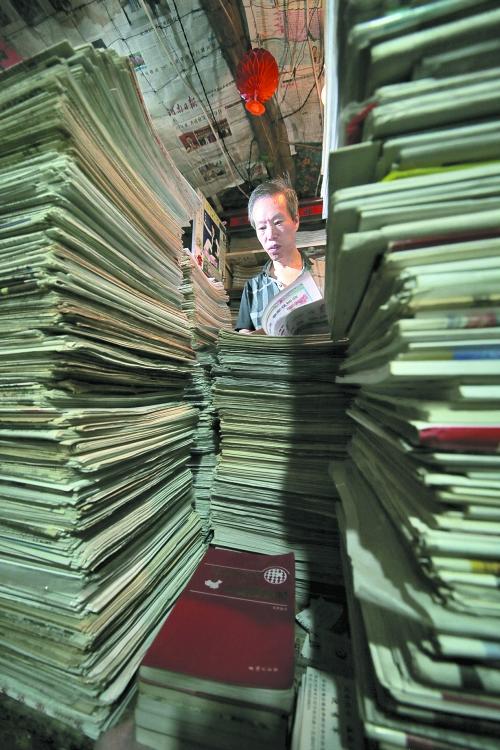 王曉民坐在寫字桌前，被報紙淹沒。