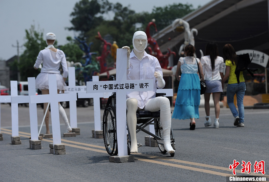 4月16日，重慶市洋人街上擺放著兩個(gè)受了傷的塑料人像“模特”，旁邊十字架上寫著向“中國(guó)式過(guò)馬路”說(shuō)不