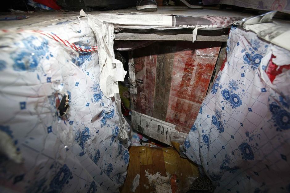 陳小龍?jiān)诔鲎馕萃?，自行又圍起一堵圍墻，安裝了一個(gè)門。圍墻上都是豎起的鐵釘，外面堆著土，鄰居猜是從地底挖出來的。洞口就在床邊，0.5米見方，深約1.5米。洞口表面一塊紙板掩蓋，打開紙板跳入洞底，是一扇小木門，木門外有插銷，可以從外面鎖上。