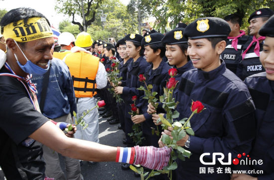 2013年12月03日,曼谷總理府與曼谷警署允許反政府示威民眾進入,雙方進入暫時“停戰(zhàn)”狀態(tài)迎接泰王生日。曼谷警察總署,女警們手持鮮花送給反政府示威民眾。圖片來源:Manish Swarup/東方IC