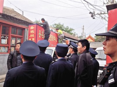 昨日下午,東城區(qū)工商、城管、公安等部門,對雍和宮附近的預測中心進行清理整頓,站在車頂?shù)膬擅と苏鸪患摇邦A測中心”的招牌。因雍和宮、白云觀等文化景點外聚集大量算命先生,被媒體稱為“算命一條街”。本版攝影/新京報記者 李寧 攝