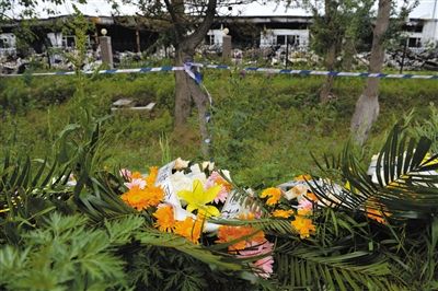 昨日，吉林省德惠市吉林寶源豐禽業(yè)有限公司燃燒事故現(xiàn)場警戒線外，遇難者家屬在路邊擺放了花圈祭奠逝去的親人。吳江 攝