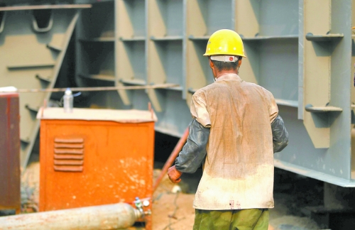 工地上，一建筑工人的衣服被汗水浸透。