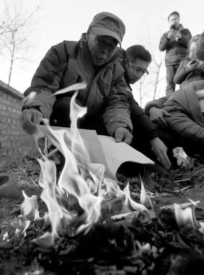 李三仁在兒子墳前焚燒再審無(wú)罪判決文書(shū)的復(fù)印件。新華社發(fā)