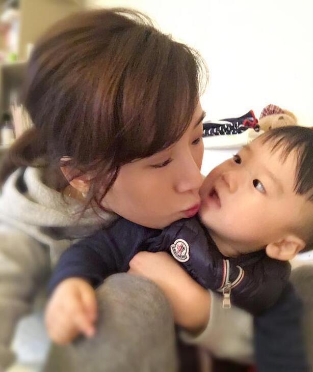 照片中李念狂吻兒子，小寶貝自顧自地玩著。