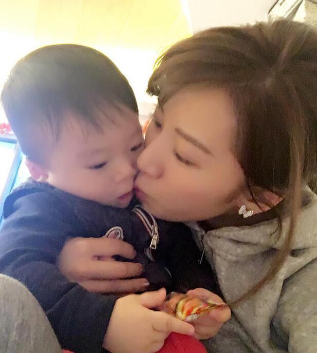 照片中李念狂吻兒子，小寶貝自顧自地玩著。