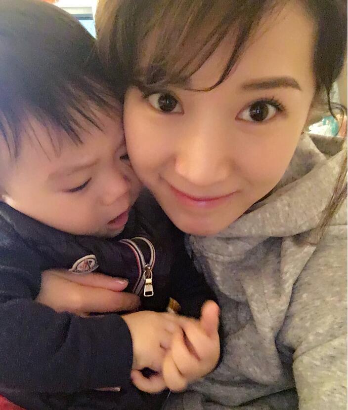 照片中李念狂吻兒子，小寶貝自顧自地玩著。