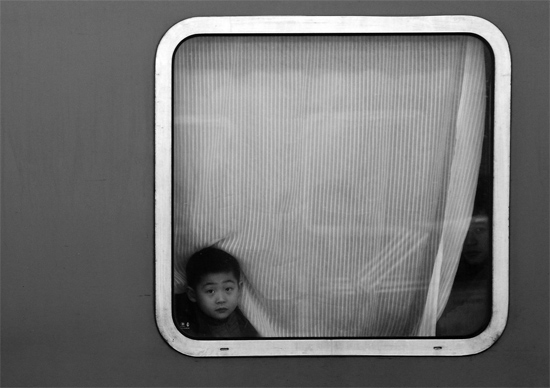 一個(gè)孩子把頭伸向窗外，他想再看送別的親人一眼