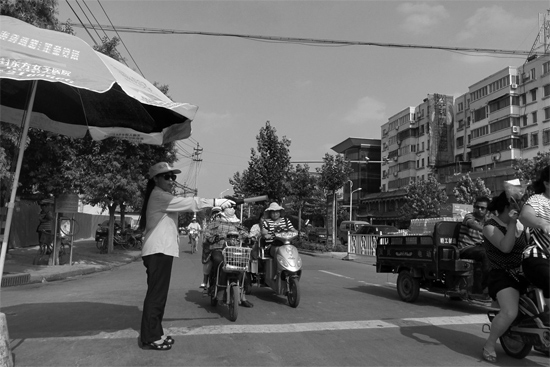 昨日，開封市區(qū)一名協(xié)管員在指揮群眾過馬路