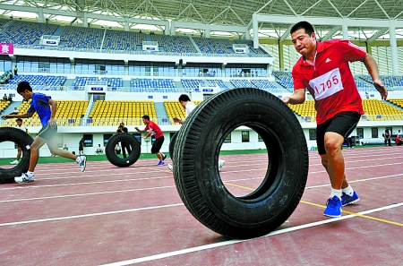 8月15日，運(yùn)動員們正在進(jìn)行推輪胎賽跑。