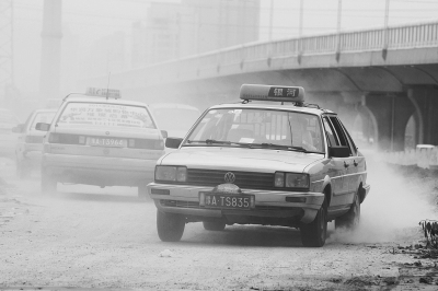 施工的道路上，車輛通過(guò)塵土飛揚(yáng)。