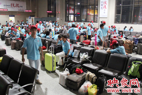 大學(xué)生志愿者在火車站候車室內(nèi)整裝待發(fā)。