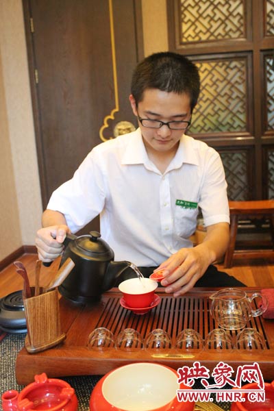 1、水壺里的水煮沸，李克勤把茶葉放進茶荷里，準備溫杯沖茶