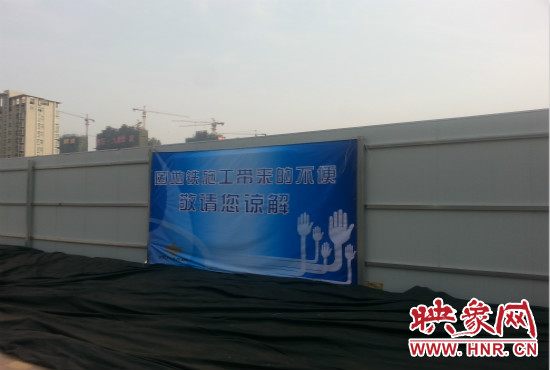 道路南側(cè)圍起了白色的圍擋，墻上標示著“因地鐵施工帶來的不便敬請您諒解”的提示牌。