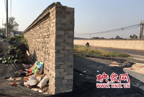一墻之隔，一邊是道路，一邊是垃圾和荒草，市民質(zhì)疑其為遮羞墻。