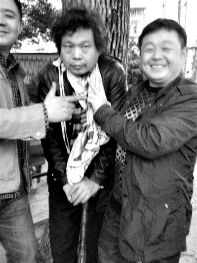 兩名接訪人員與患有癌癥的訪民段新德合影時，面帶笑容擺出勝利的手勢。