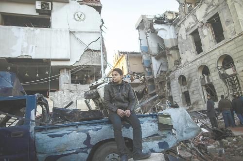 埃及曼蘇拉市警察局24日遭汽車炸彈襲擊，被疑是穆兄會(huì)的報(bào)復(fù)。圖為一名男子在被炸毀的警察局前。