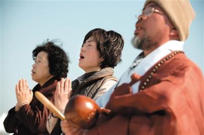 23日，一名僧侶引領人們?yōu)樗勒咂矶\。