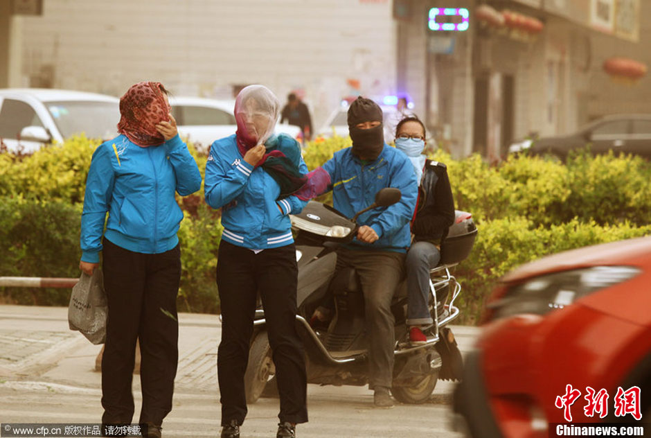 2014年04月23日，新疆維吾爾自治區(qū)吐魯番地區(qū)，市民戴著口罩行走在大風(fēng)沙塵中的吐魯番市街頭。