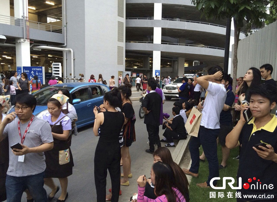 當(dāng)?shù)貢r(shí)間2014年5月5日，泰國清萊，工人們站在一棟大樓外避難。