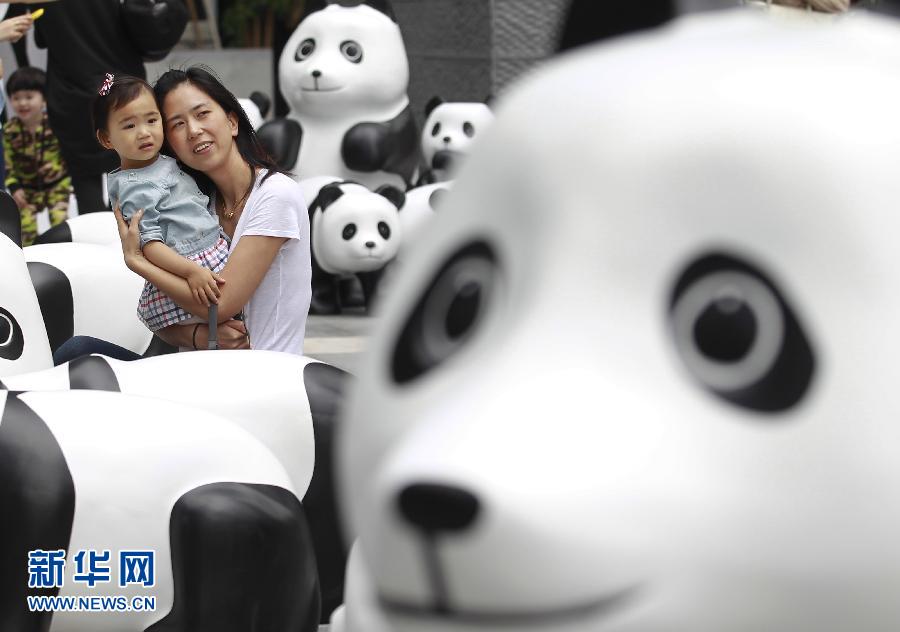 6月2日，一位家長帶著孩子在上海街頭和大熊貓模型合影。