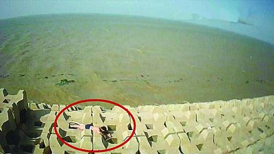 孫正龍游上岸，趴在海邊精疲力盡。