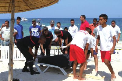 6月26日，在突尼斯蘇塞，救生員和醫(yī)務(wù)人員在發(fā)生襲擊事件的海灘運(yùn)送一名死者的遺體。新華社發(fā)