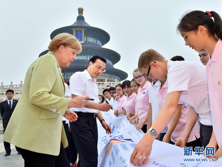 李克強(qiáng)同默克爾在紀(jì)念橫幅上簽名。