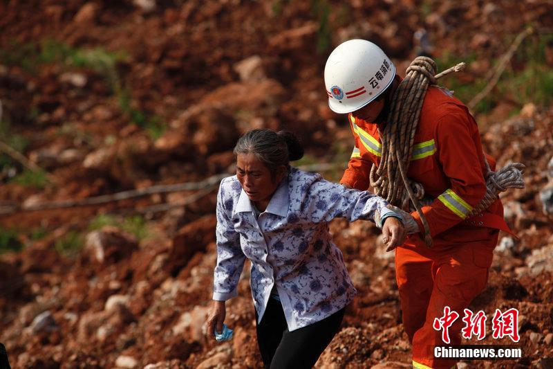 一位消防戰(zhàn)士將一位失去親人的老人扶離滑坡點。