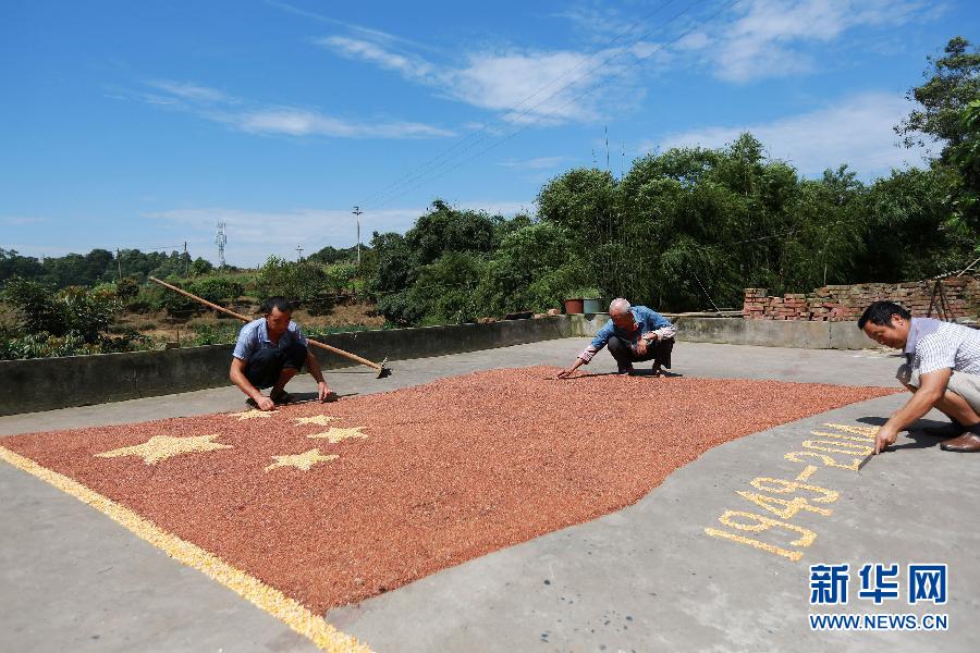 村民馬玉明（左一）用豐收的高粱和玉米在院壩里擺國旗為祖國慶生。