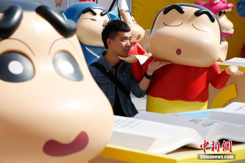 4月22日，游客與蠟筆小新合影?！跋灩P小新25周年紀(jì)念特展”日前在北京開展，吸引了不少市民游客。