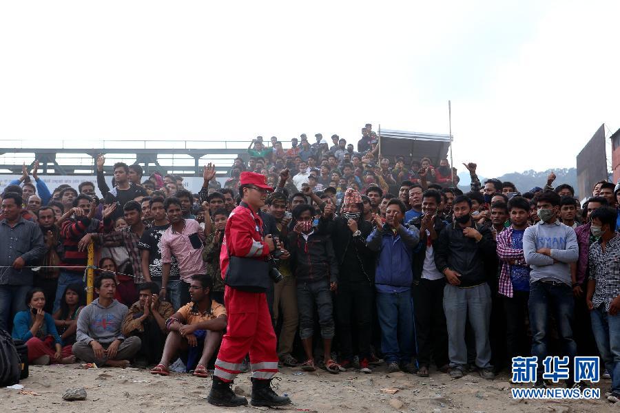 圍觀的尼泊爾民眾在中國國際救援隊(duì)成功搜救出幸存者后向搜救隊(duì)員歡呼致意。